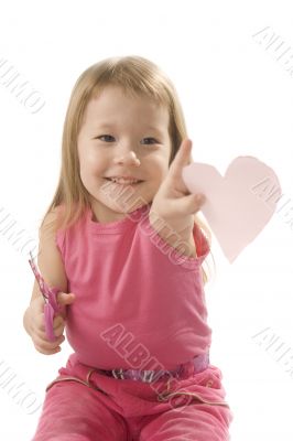 pretty small girl is cutting paper heart shape