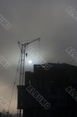 Gray sunset sky with lifting construction cranes