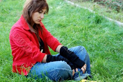 young woman sitting on grass, sad expression