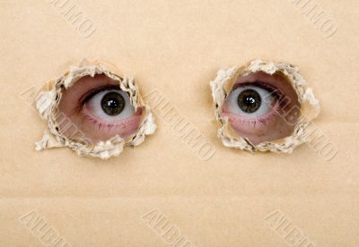 Eye looking from a holes in a cardboard
