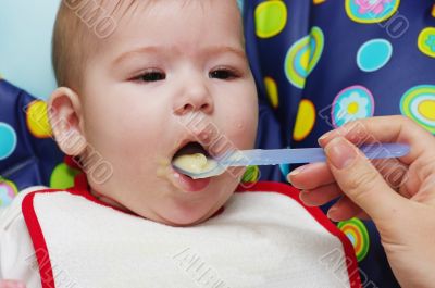 Mother feeding baby food to baby