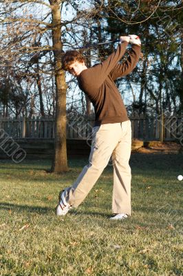 Youth golfer hitting iron