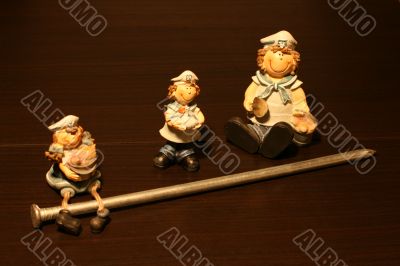 Three figures near a big nail