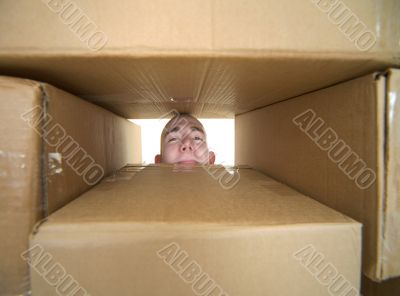 Face looking trough window in pile cardboard boxes