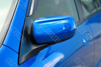 Right side mirror of shiny blue car