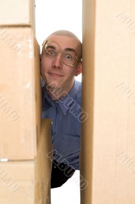 Male face clamping between cardboard boxes