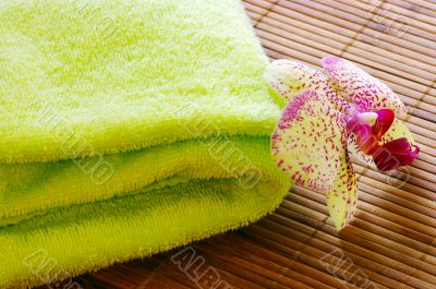 Spa concept of towel and orchid on bamboo mat