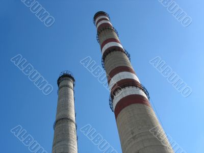 Two industrial chimneys with no smoke over blue sky