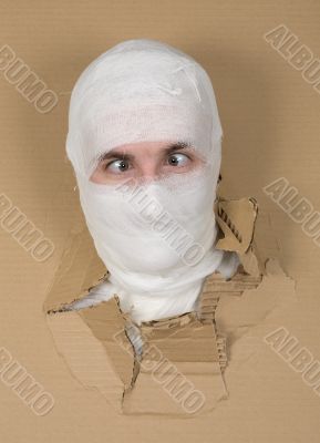 Male face on bandage in carton hole Male face on bandage in carton hole
