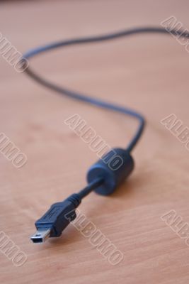 Black USB cable on wood background