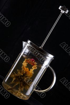 French-press with tea in black background