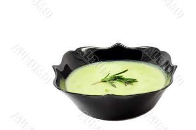 Green soup on the black plate on whote background