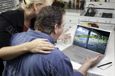 Couple In Kitchen Using Laptop - Real Estate and Vacations