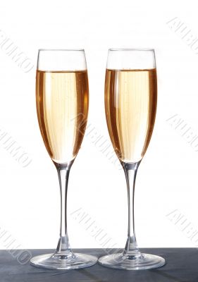 Two elegant champagne glasses on a dark surface