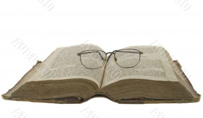 Vintage open book bible open and glasses on it isolated over whi