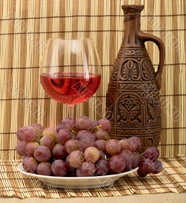 Carafe, grape and goblet on mat