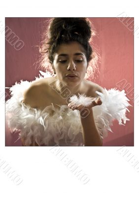 Attractive girl blowing feathers from hand.