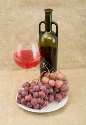 Still-life with a glass of red wine, bottle and grapes