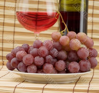 Glass bottle, goblet and grape