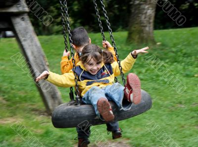 Little girl and boy on a swing
