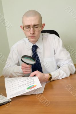 Boss with a magnifier on a workplace