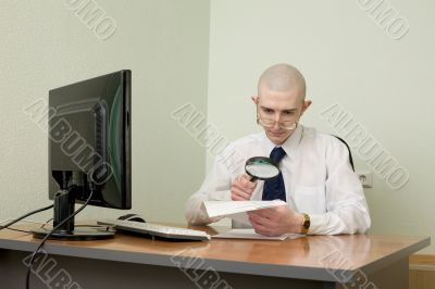 Boss with a magnifier on a workplace