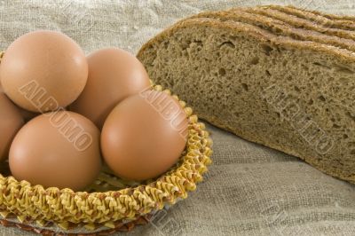 Many fresh rural eggs lying in a wattled small basket near to fr