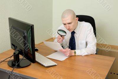 Businessman with a magnifier on a workplace