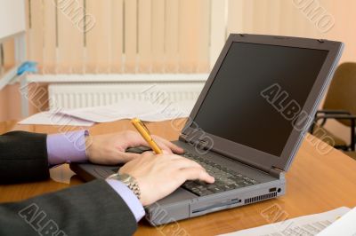 Laptop and hands with a pen