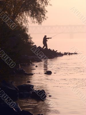 Silhouette of alone fisher near sunset river