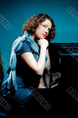 girl with fur scarf near piano thinking