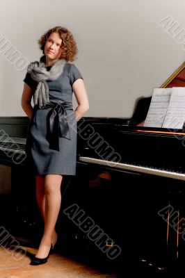 young lady in dress standing near piano