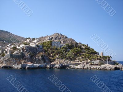 Hydra rocky beach with old buildings