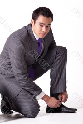 Strong young indonesian man in a suit tying his shoes