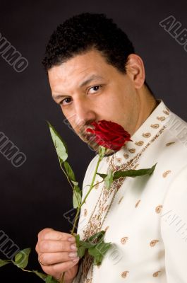 aruban male is smelling a beautiful red rose