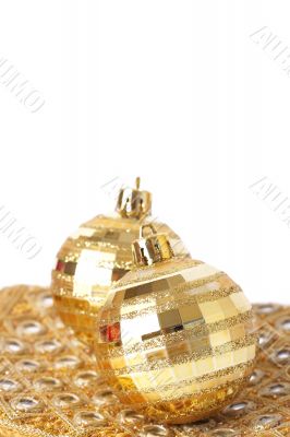 Two gold Christmas baubles on pretty material