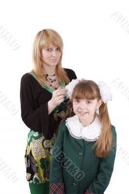 Mom is brushing young schoolgirl`s hair.