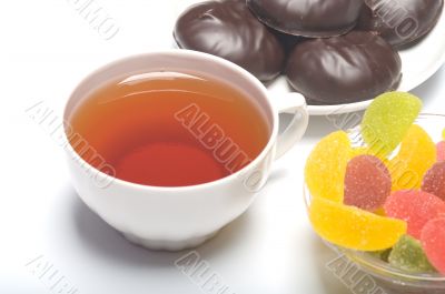 Cup with tea, a zephyr and fruit candy.