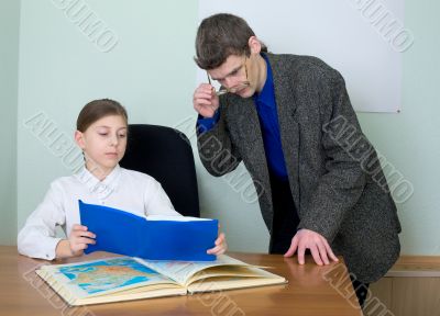 Tutor and schoolgirl with book and atlas