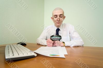 Boss with a magnifier on a workplace