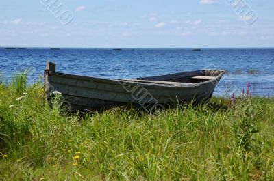 Old wooden fishing boat on the lake bank