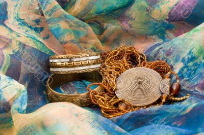 two bracelets and a necklace on a multicolored silk