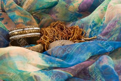 two bracelets and a necklace on a multicolored silk