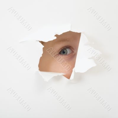 Eye looking through hole in sheet of paper