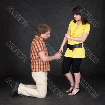 Man is kneeling to the young woman, being sorry
