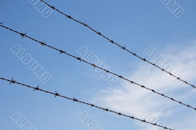 Three strands of rusty barbed wire over sky
