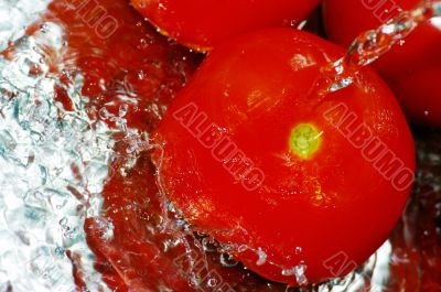 Fresh tomatoes under running tap with water drops