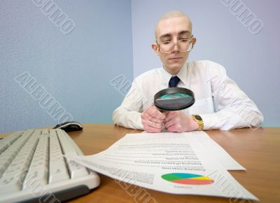 Boss with a magnifier on a workplace