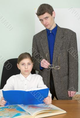 Tutor and schoolgirl with book and atlas