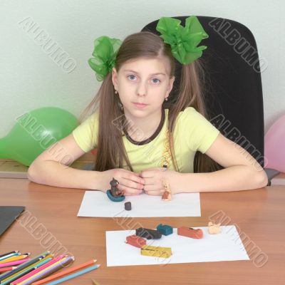 Girl sitting at a table with plasticine Girl sitting at a table with plasticine